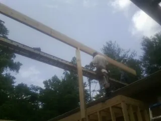 Carpenter setting a ridge beam over a new addition frame — Ice Dam Removal by Roofing Brothers in Bonita