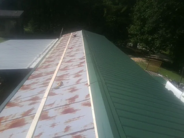 Old rusted panels beside newly installed green metal roofing — Wind Damage Roof Repair by Roofing Brothers in Bonita