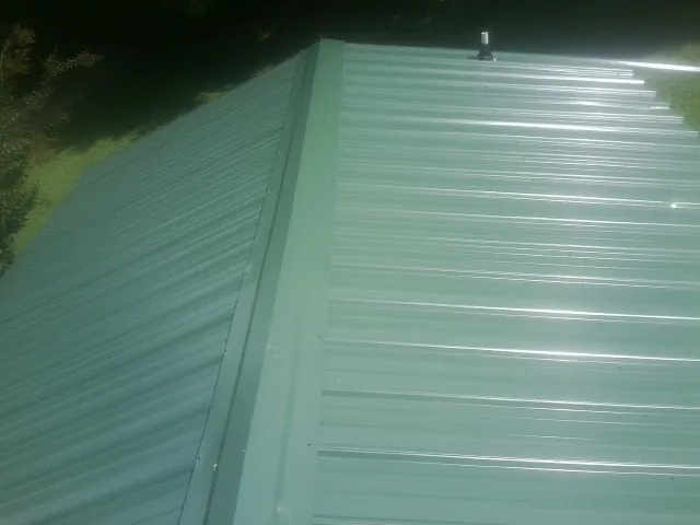 New green metal panels meeting at the ridge of a roof — Flat Roof Repair work by our crew in Bonita