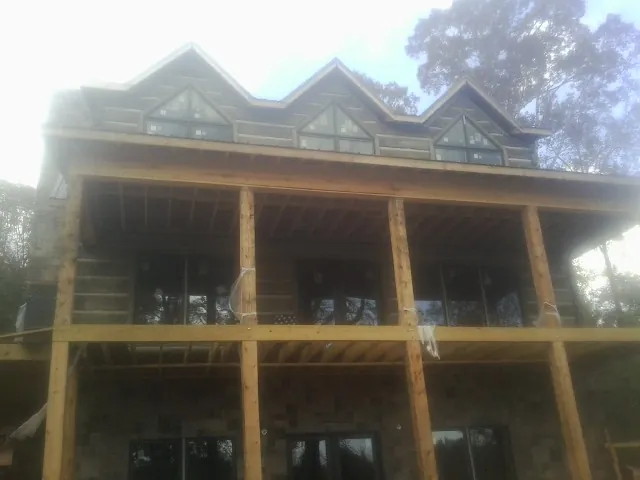 Dormers and porch framing on a large log home under construction — Roof Coating work by our crew in Bonita
