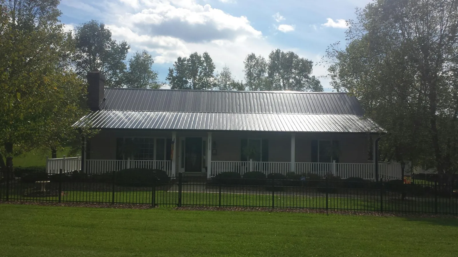 Gray metal roof on a brick ranch with a full width front porch — Gutter Guard Installation work by our crew in Bonita