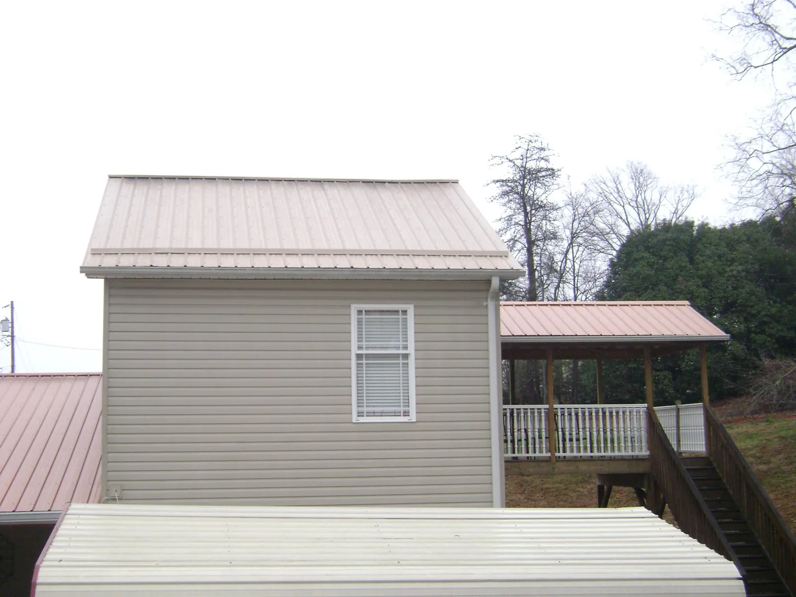 Tan metal roofs on a two story addition and attached porch, from a Roof Replacement job in Bonita