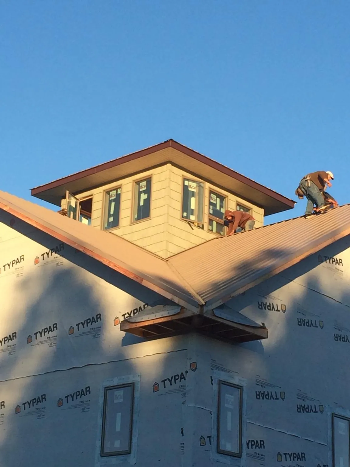 Roofers working around a rooftop cupola on a new metal roof at sunset — Roof Waterproofing in Bonita by Roofing Brothers